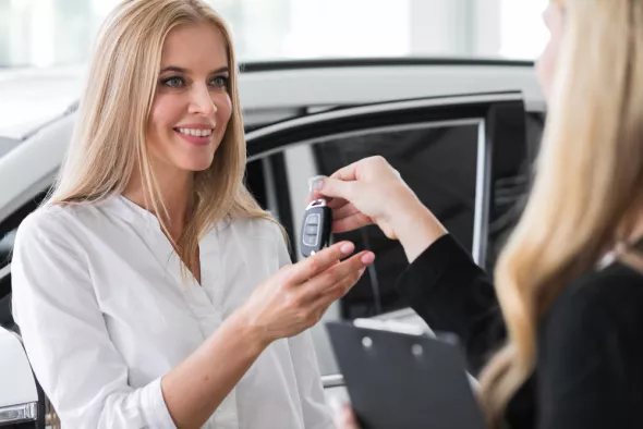 Zadowolona kobieta odbiera auto od przedstawicielki wypożyczalni samochodów Kaizen Rent