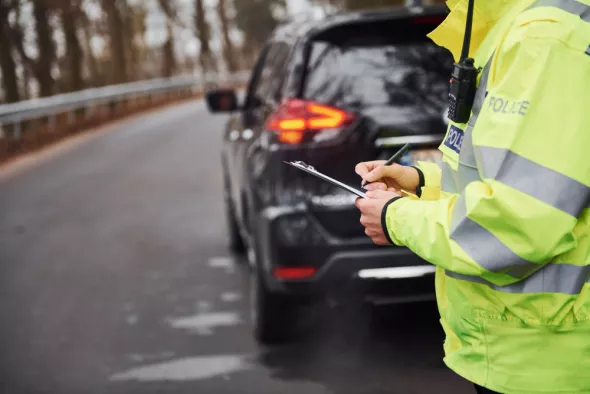 Policjant wypisuje mandat. Sprawdź aktualny taryfikator mandatów w 2025 roku!