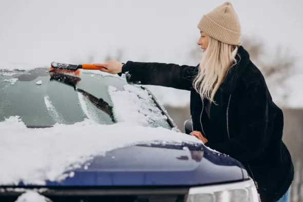 Kobieta odśnieża auto przed wyruszeniem w trasę