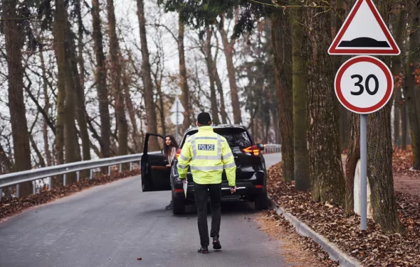 Policjant idzie do zatrzymanego kierowcy za łamanie nowych przepisów drogowych 2025