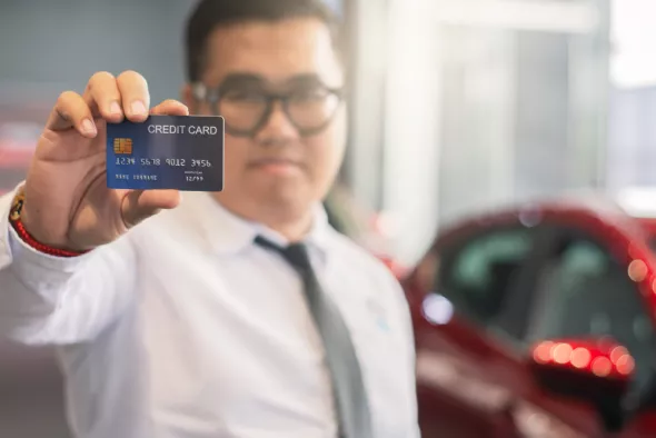 Mężczyzna w wypożyczalni samochodów płaci za auto premium kartą kredytową