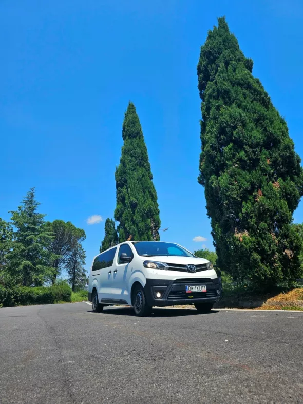 Toyota Proace Verso z wypożyczalni samochodów Kazien Rent na tle wysokich tuj