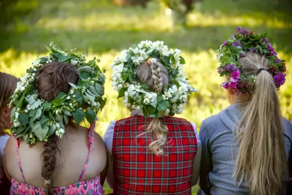 Three women wearing flower wreaths during Wianki festival 