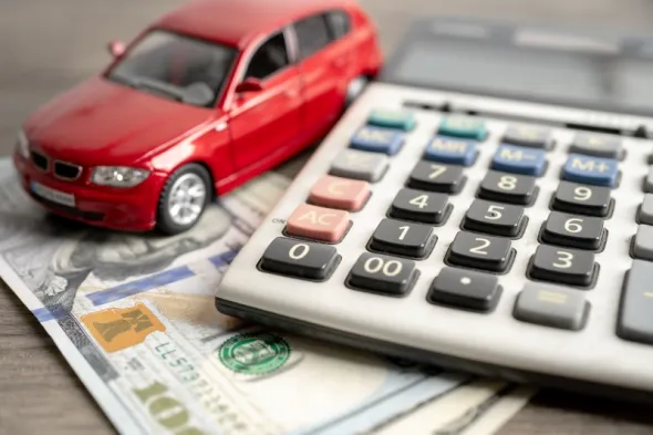 Czerwony resorak, pieniądze oraz kalkulator jako symbol tematu: najem samochodu a koszty uzyskania przychodu