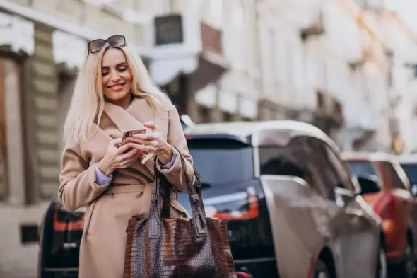 A Kaizen Rent customer in Poznań checks the route on her phone next to the rented car.