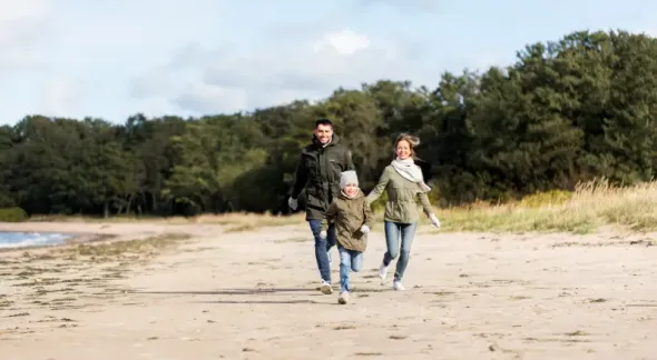 Happy family running along the autumn beach in Gdańsk, Poland