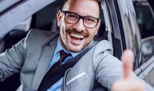 Clear and transparent cooperation is our motto! A man in a Kaizen Rent car, with a thumbs up.