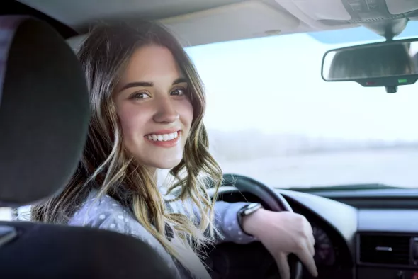 Uśmiechnięta kobieta jadąca samochodem z wypożyczalni Kaizen Rent