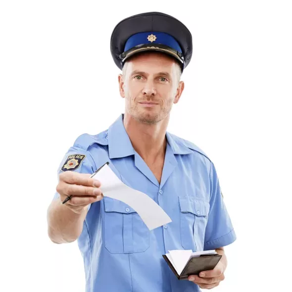 Policjant wręcza mandat. Taryfikator mandatów 2025: Najczęstsze wykroczenia kierowców w Polsce