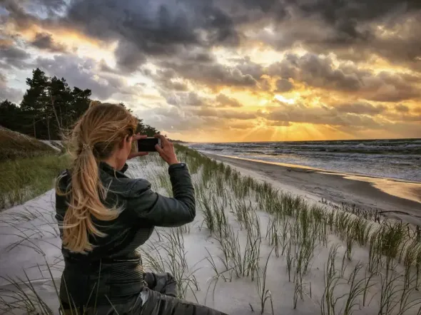 Man photographing a Polish beach at sunset