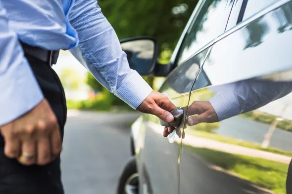 Man unlocking a rental car in Poland, highlighting insurance coverage and protection before starting the trip.
