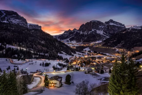 Mesmerizing view houses fields covered snow surrounded by mountains trees.