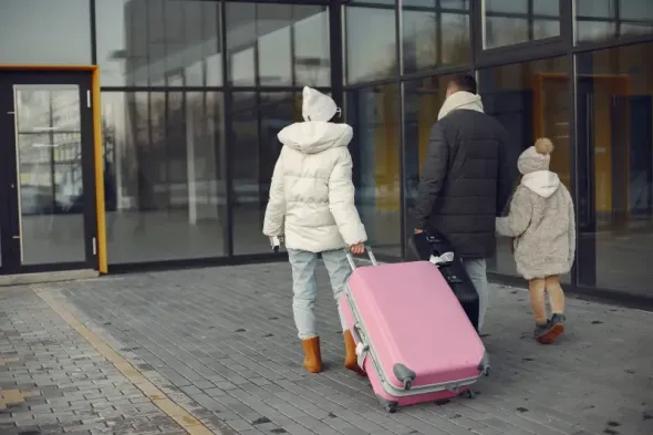 A family with luggage at Kraków-Balice Airport begins their journey in a hired car.