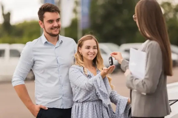 Rental agent handing car keys to a couple
