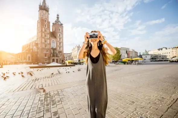 Young tourist standing in front of St. Mary’s Basilica in Krakow at sunrise after traveling from Warsaw