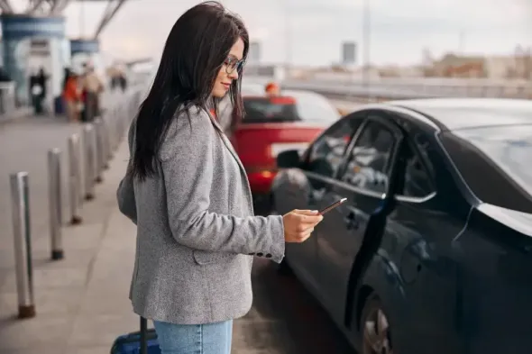 Young woman walking toward a parking area near Kraków Airport.