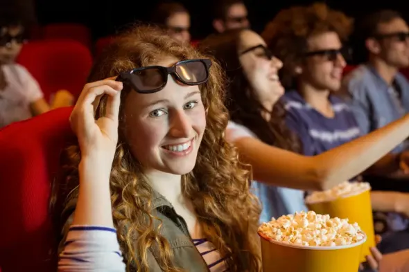 Young woman watching a movie in cinema, focused on the screen