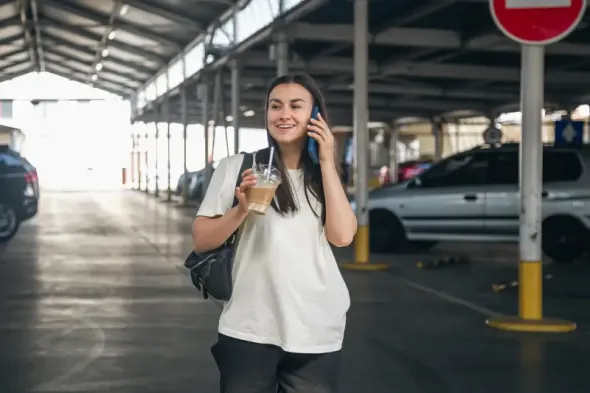 A passenger in the parking lot of Gdańsk airport with a coffee before departure.