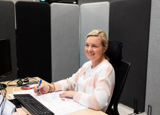 Wypożyczalnia samochodów Kaizen Rent - uśmiechnięta Agnieszka pracująca przy komputerze w nowej siedzibie firmy