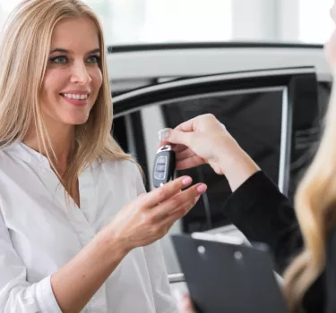 Zadowolona kobieta odbiera auto od przedstawicielki wypożyczalni samochodów Kaizen Rent