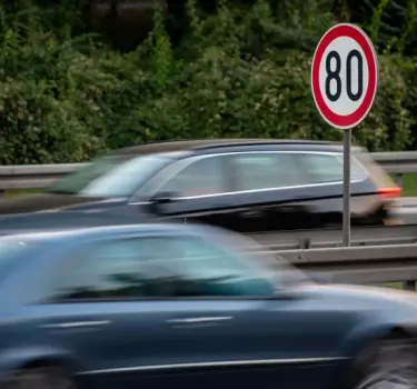 A speed limit sign indicating 80 km/h on a busy road in Poland, with many cars travelling along the motorway.
