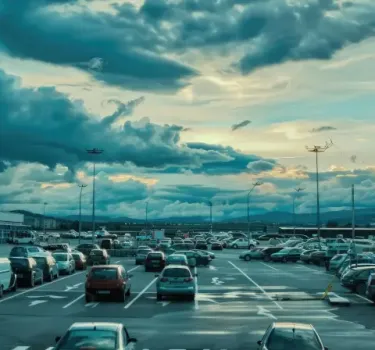 A plane landing at the airport next to the passenger parking lot