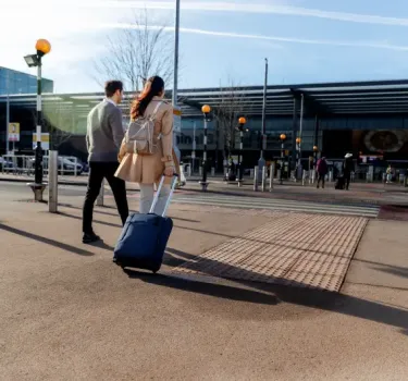 Travelers carrying baggage on their way to the terminal at Kraków Airport Balice.