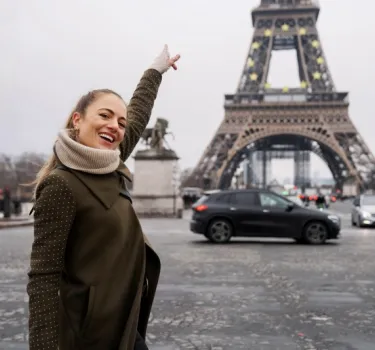 młoda kobieta podczas podróży po stolicy Francji, robi pozuje do zdjęcia z wieżą Eiffla w Paryżu