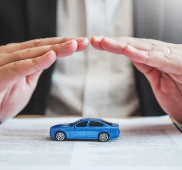 Hands protecting a rental car from above, representing insurance coverage and financial security when renting a car in Poland.
