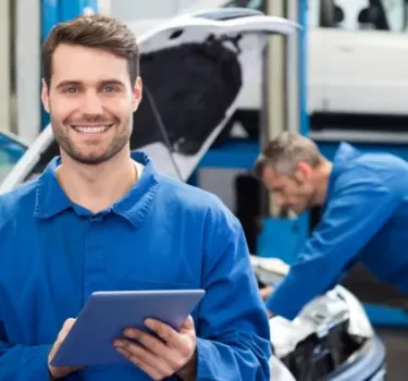 Uśmiechnięty mechanik przypomina o zmianach w przeglądach technicznych samochodów