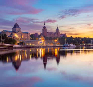 Sunset view Szczecin riverfront along oder river Poland featuring illuminated waly. 