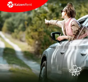 Wiosenne słońce i uśmiechnięta dziewczyna wychylająca się z okna wynajętego auta, która wskazuje kierunek dalszej podróży