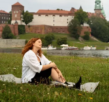 A woman in a meadow in front of the Wawel Castle in Krakow