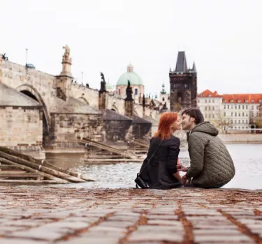 Para młodych ludzi siedząca nad rzeką w Pradze, stolicy Czeskiej Republiki