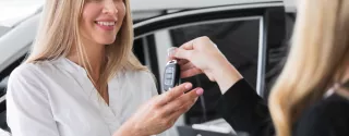 Zadowolona kobieta odbiera auto od przedstawicielki wypożyczalni samochodów Kaizen Rent