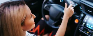 Kobieta w samochodzie patrzy na kokpit, kontrolując prędkość. Ile wynosi mandat za przekroczenie prędkości w 2025 roku?