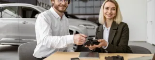 A woman watches as a man makes a card payment on a terminal while renting a car.