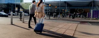 Travelers carrying baggage on their way to the terminal at Kraków Airport Balice.