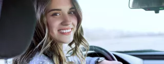 A smiling woman driving a Kaizen Rent car