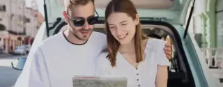 A couple looking at a city map while touring in a hire car