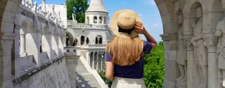 Młoda kobieta zwiedza Budapeszt. Wakacje samochodem po Europie – gdzie warto pojechać i jak zaplanować trasę?