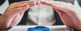 Hands protecting a rental car from above, representing insurance coverage and financial security when renting a car in Poland.
