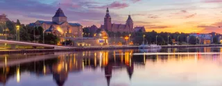 Sunset view Szczecin riverfront along oder river Poland featuring illuminated waly. 