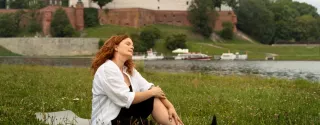 A woman in a meadow in front of the Wawel Castle in Krakow
