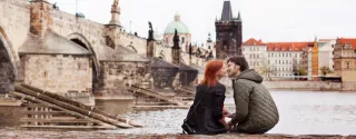 Para młodych ludzi siedząca nad rzeką w Pradze, stolicy Czeskiej Republiki