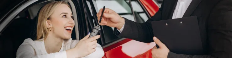 Zadowolona kobieta oddaje kluczyki po – zwrot samochodu po wynajmie długoterminowym