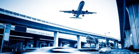 Airplane flying above a blurred city street scene near Kraków Airport.