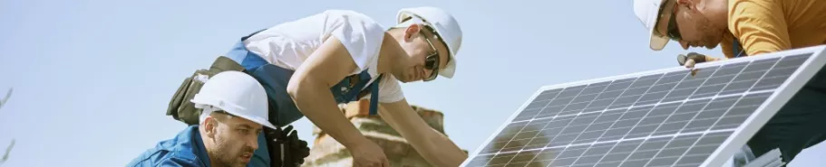 Workers install photovoltaic panels on the roof