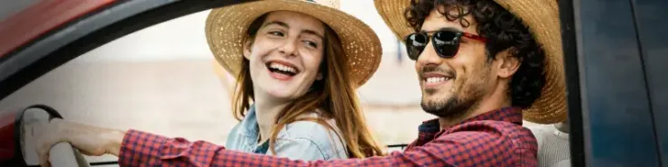 Para podróżników  jedzie czerwonym samochodem na romantyczny weekend; klimat przygody i planowania wycieczki.