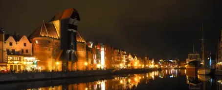 Night view of Gdańsk Old Town with historic buildings reflected in the Motława River